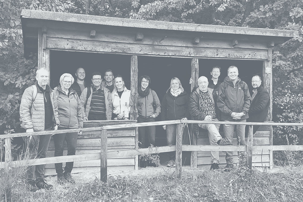 Foto de grupo de los trabajadores de Extruder Experts frente a una cabaña de madera