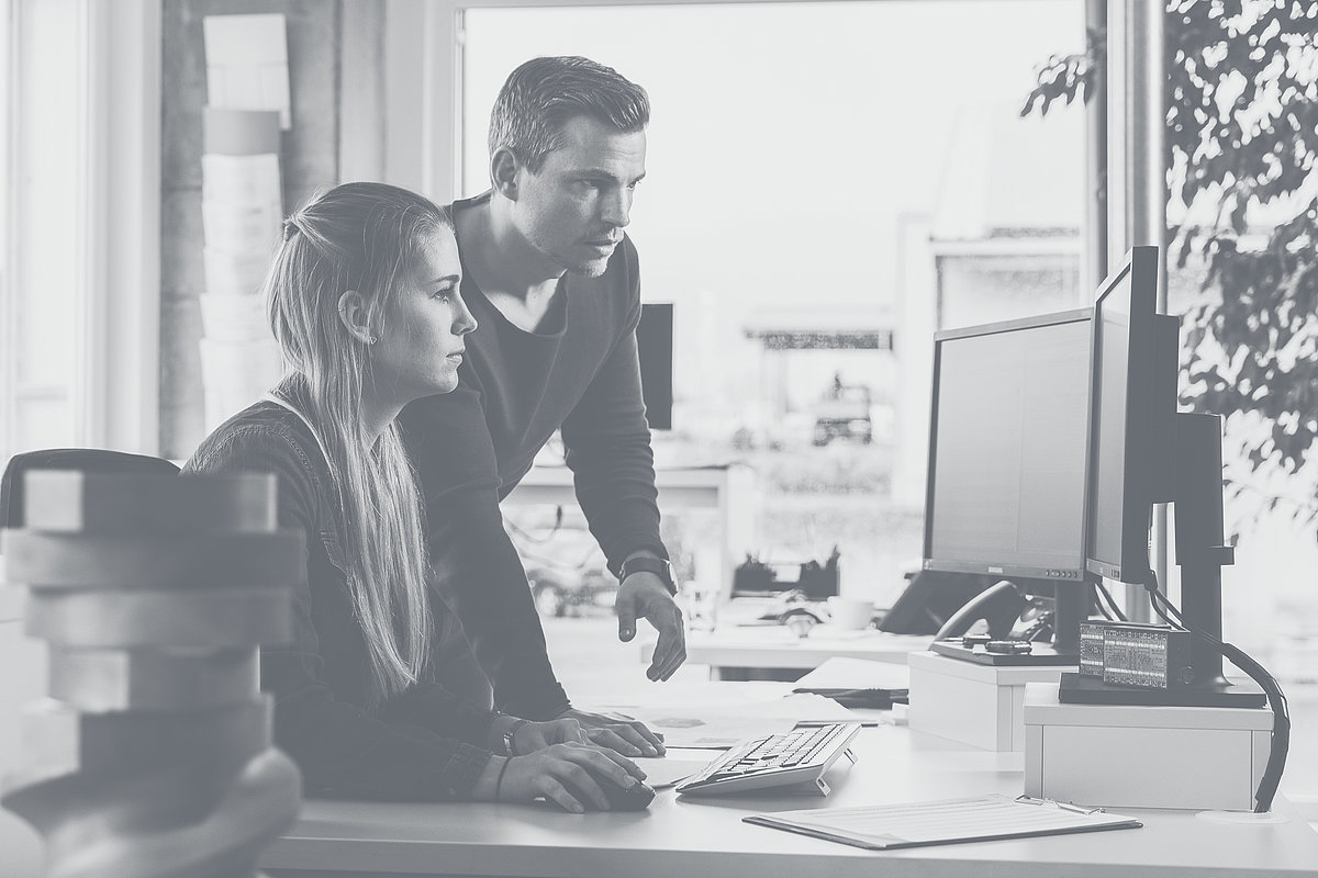Two employees of Extruder Experts discuss in front of a monitor